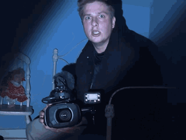 a man is holding a camera that says canon on the front