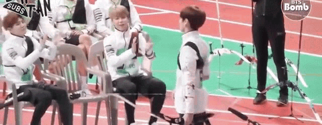 a group of people are sitting in chairs on a track while a man in a wheelchair is holding a bow .