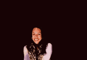 a woman wearing a leopard print vest and a white shirt is smiling