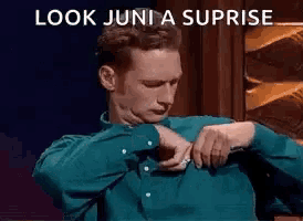 a man is sitting in a chair looking at his watch and says `` look juni a suprise '' .