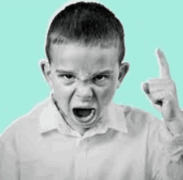 a young boy is making a funny face and pointing his finger up .