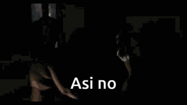 a man and a woman are dancing in a dark room with the words `` asi no '' written on the screen .
