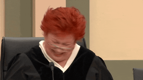 a woman with red hair is wearing glasses and a judge 's gown