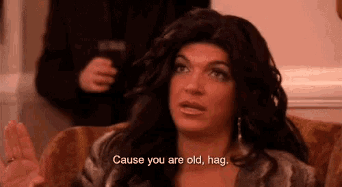 a woman is sitting on a couch and saying `` cause you are old , hag '' .