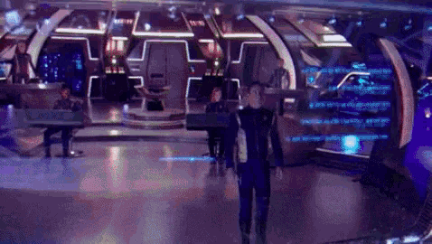 a man is walking through a futuristic room with a lot of lights on .