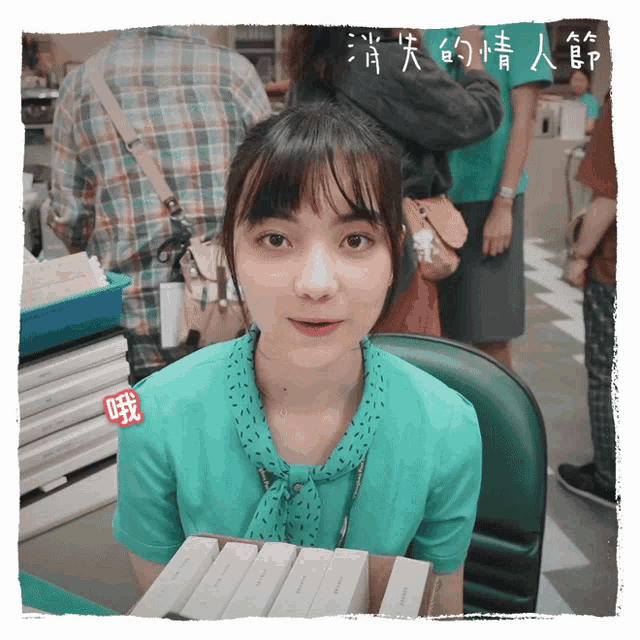 a woman in a green shirt sits in front of a stack of boxes