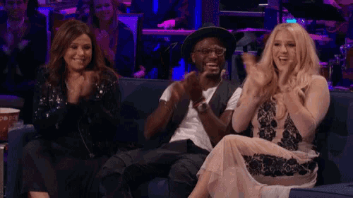 a group of people sitting on a couch clapping and smiling