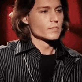 a close up of a man wearing a striped shirt and a black shirt with a necklace .