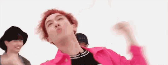 a man with red hair is wearing a pink jacket and a black hat while dancing .