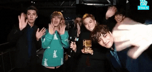 a group of people are posing for a picture with a vlive tv logo in the corner