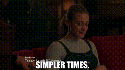 a woman is sitting on a red couch with the words `` simpler times '' written on the bottom .