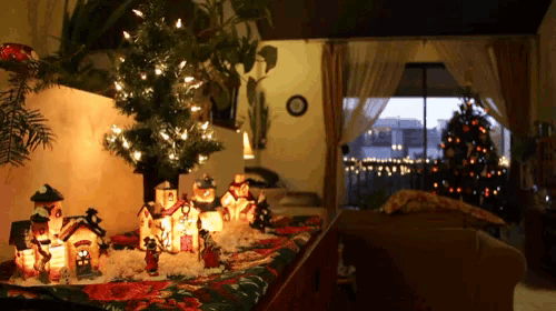 a living room decorated for christmas with a clock on the wall and a christmas tree in the background