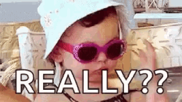 a little girl wearing sunglasses and a hat is making a really ? gesture .