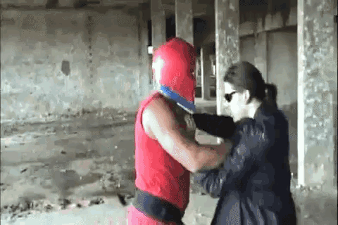 a man in a red helmet is fighting a woman in a black coat .