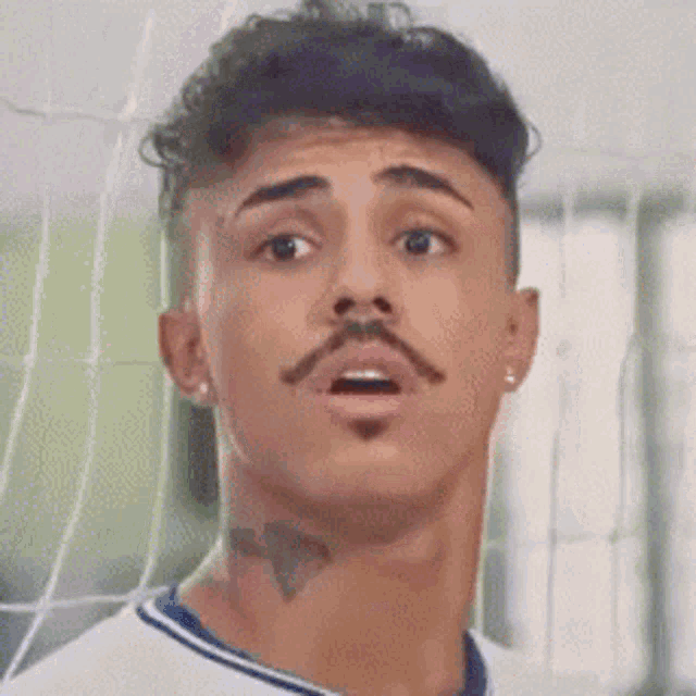 a man with a mustache and a tattoo on his neck is wearing a white shirt .