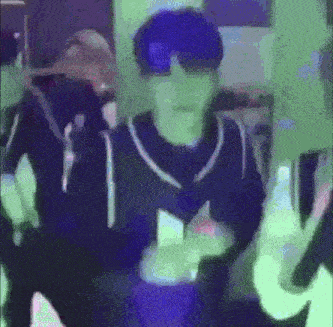 a man wearing sunglasses and a mask is dancing in a dark room .