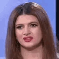 a woman with long brown hair is making a funny face while looking at the camera .