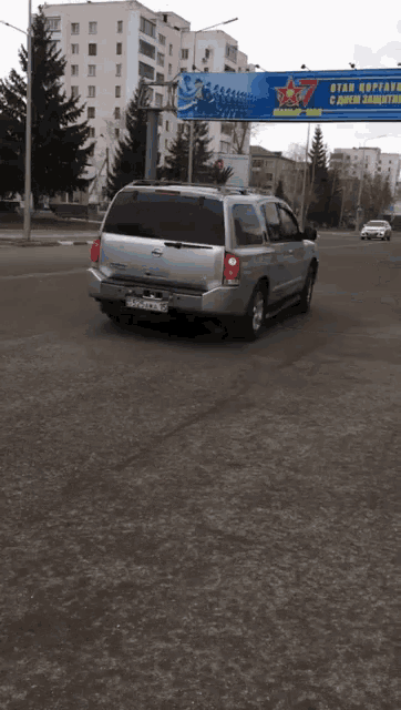 cars are driving under a billboard that says ' otan koptavms etniners ' on it