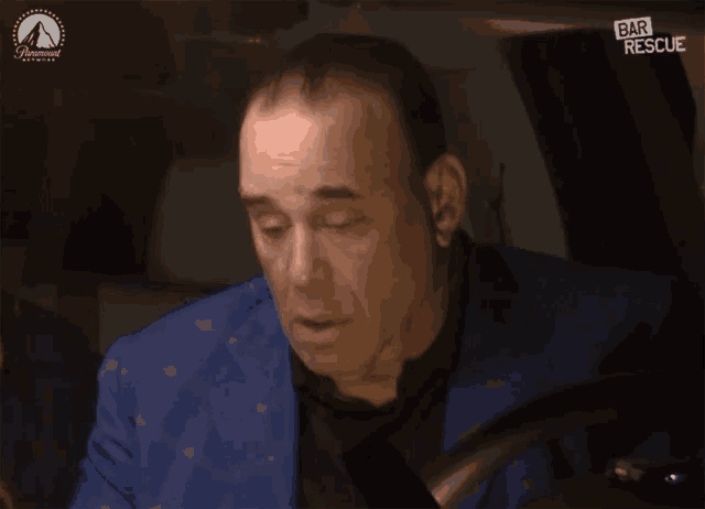 a man in a blue suit is driving a car with the words bar rescue on the bottom