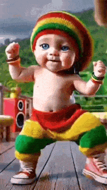 a baby wearing a rasta hat and pants is dancing on a wooden floor .