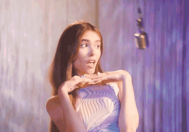 a woman in a purple dress is making a surprised face in front of a microphone