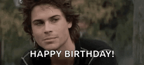 a man with long hair is sitting down and saying `` happy birthday '' .