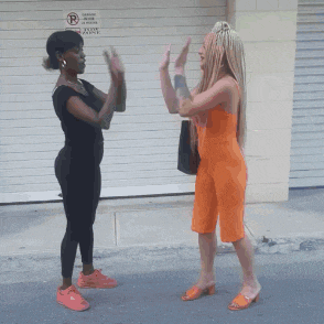 two women are clapping in front of a garage door