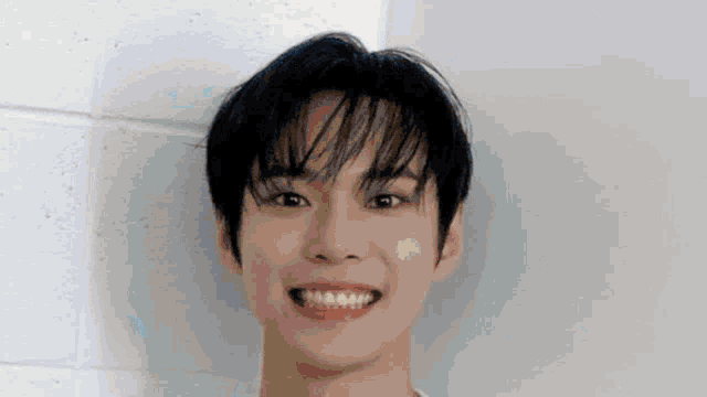 a young man with braces on his teeth is smiling while standing next to a wall .
