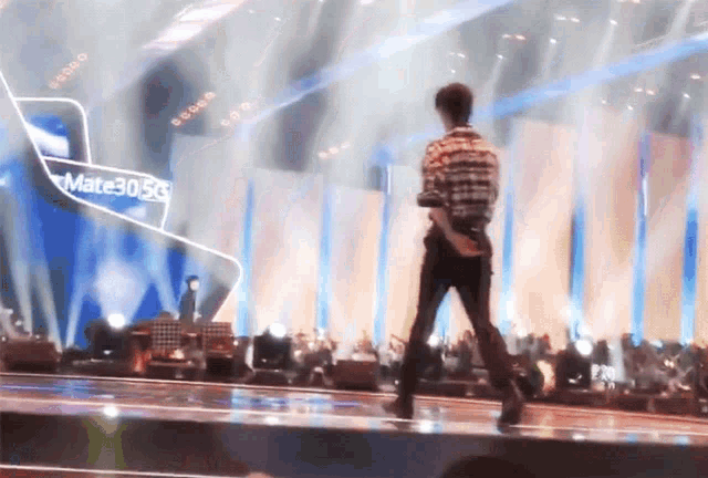 a man is walking on a stage with a sign that says mate30 5g in the background