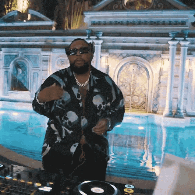 a man in a skull shirt stands in front of a pool