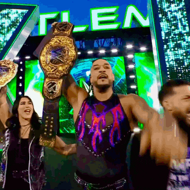 a man is holding a wrestling championship belt in front of a sign that says " t-len "