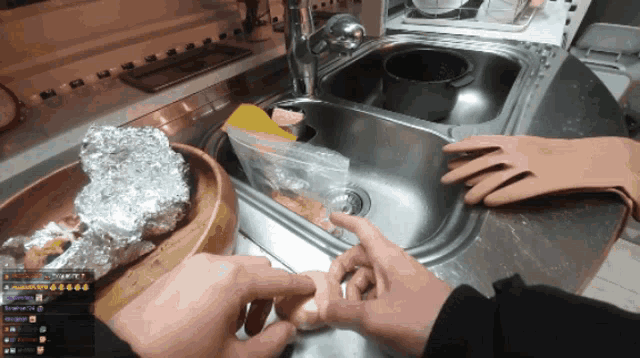 a person wearing gloves is washing a potato in a kitchen sink