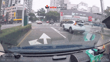 a car is driving down a street with a nissan building behind it