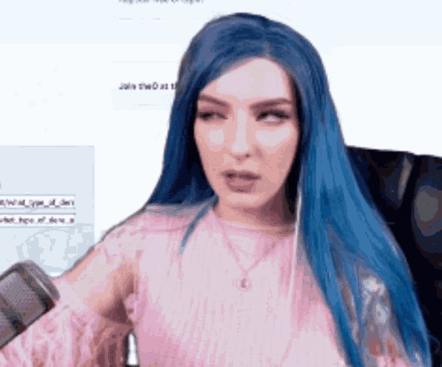 a woman with blue hair is wearing a pink top