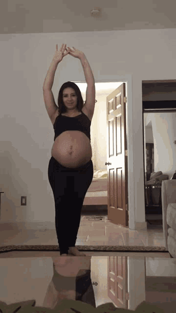 a pregnant woman stretches her arms over her head