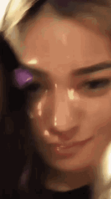 a close up of a woman 's face with a purple object in her eyes .