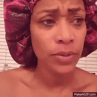 a woman is wearing a pink shower cap on her head and making a funny face .