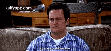 a man wearing glasses is sitting on a couch and saying " ooh , don 't open that door " .