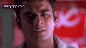 a close up of a man 's face with a red background and a sign in the background .