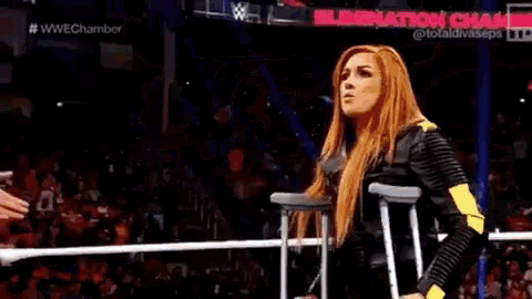 a woman is standing in a wrestling ring with a rope around her neck .