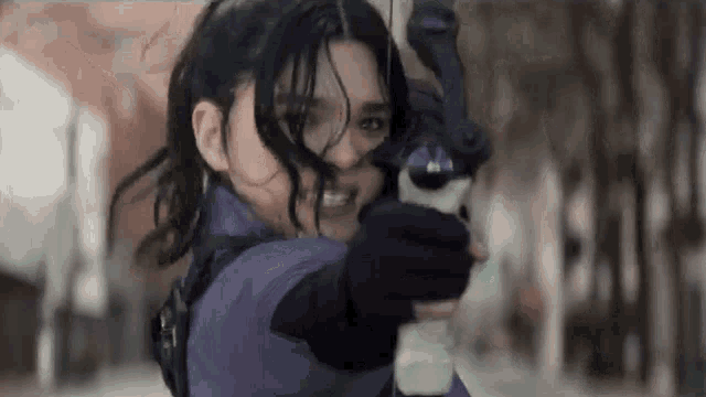 a woman is holding a bow and arrow and pointing it at the camera .