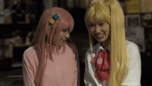two girls in wigs are sitting next to each other and smiling at each other .