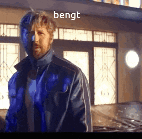 a man in a blue jacket is standing in front of a building and the word bengt is on the screen