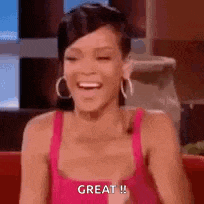 a woman in a pink tank top is sitting on a couch laughing and saying `` great '' .