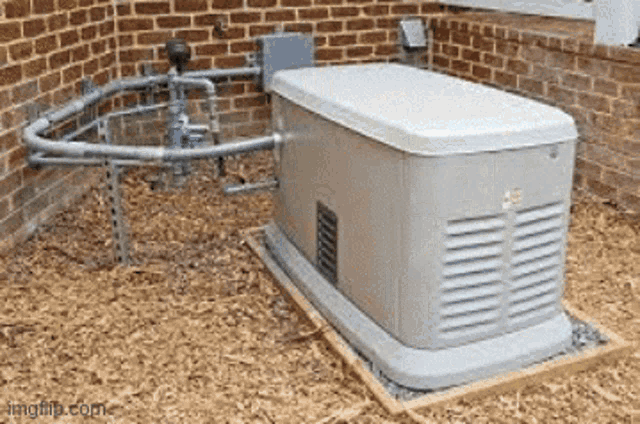 a generator is sitting outside of a brick building on a pile of wood chips