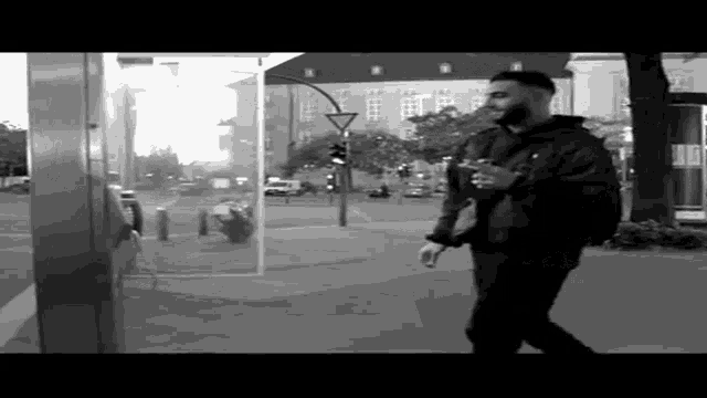a man in a black jacket is walking down the street