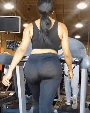 a woman is walking on a treadmill in a gym
