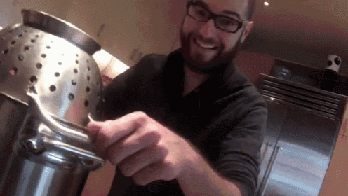 a man with glasses and a beard is holding a metal object