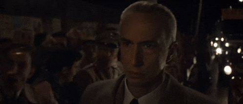 a man in a suit and tie stands in a dark room
