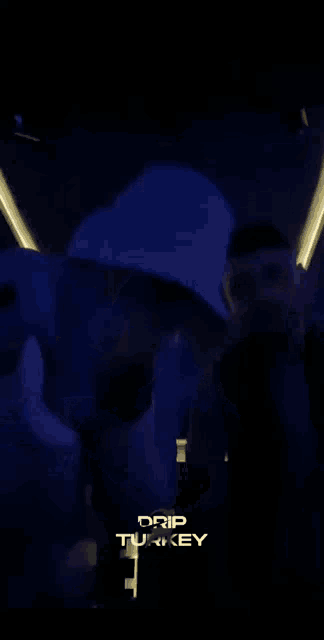 a man in a bucket hat is dancing in a dark room with drip turkey written on the bottom right